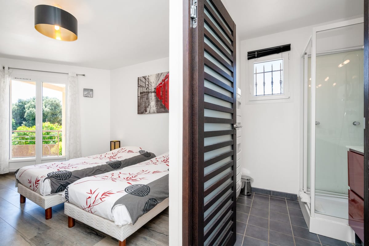 A twin bedroom in one of the private villas, with an en-suite shower room through a louvred partition.