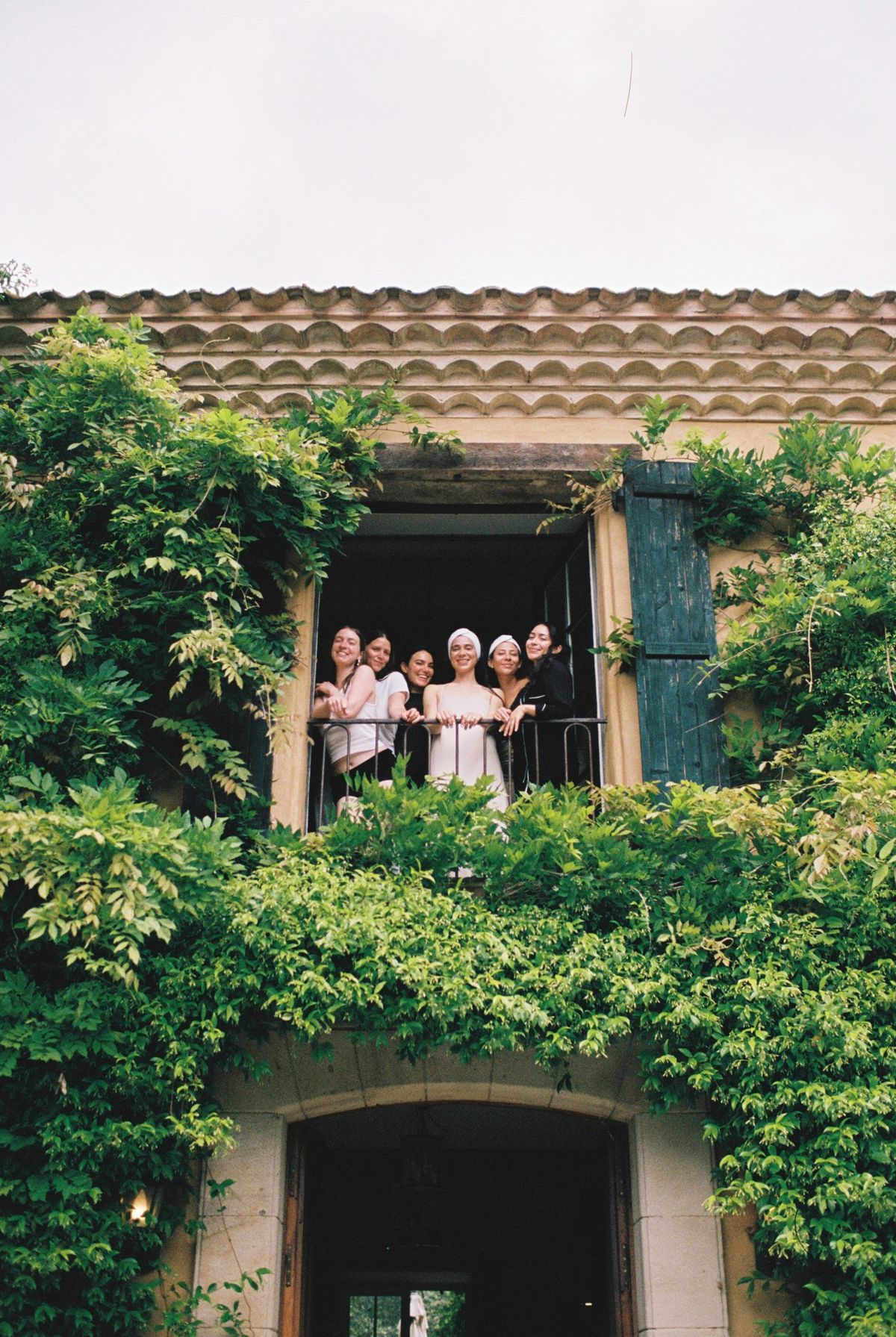 The bridal party on a first-floor balcony, framed by climbing greenery