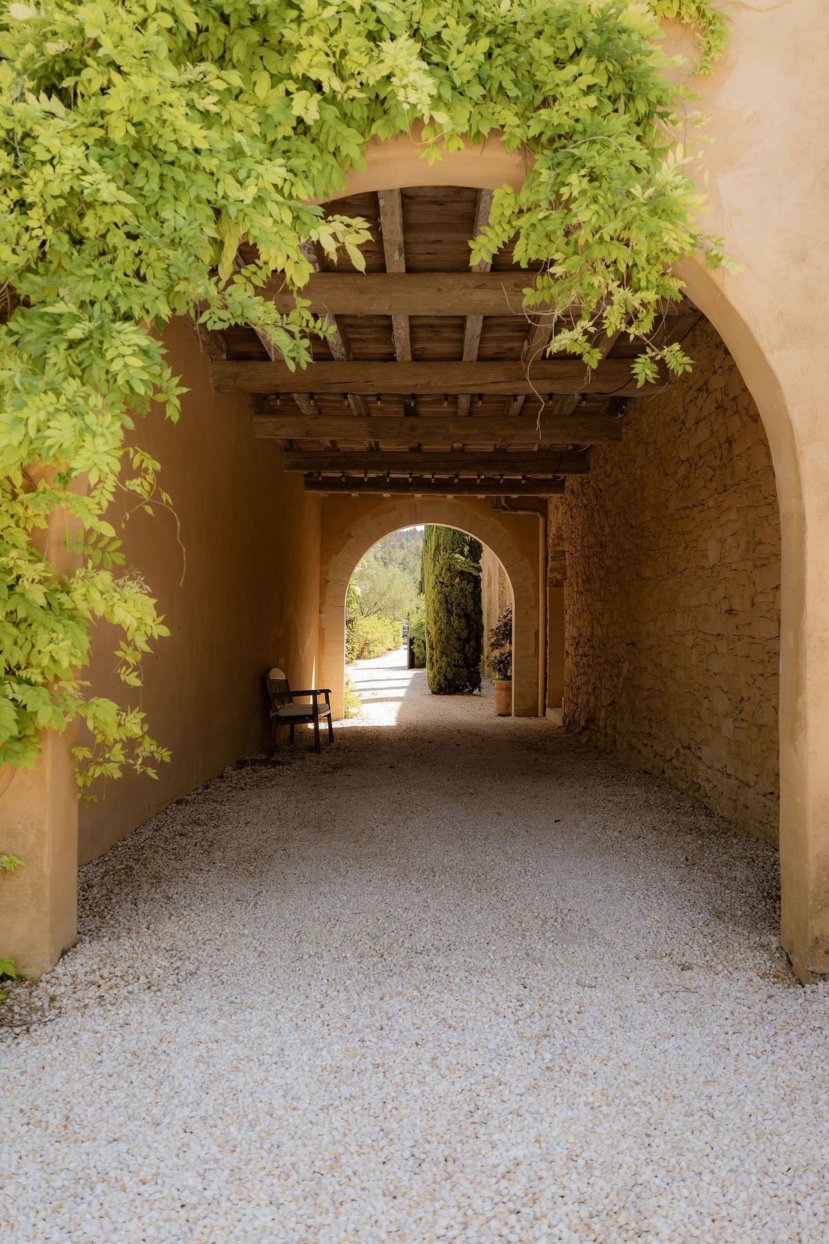 A beamed passage floored in gravel leads through to the gardens, wisteria over the arch