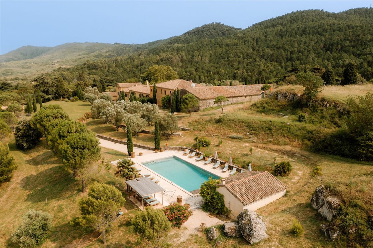 Aerial view over the pool and pool house towards the main buildings and the hills beyond