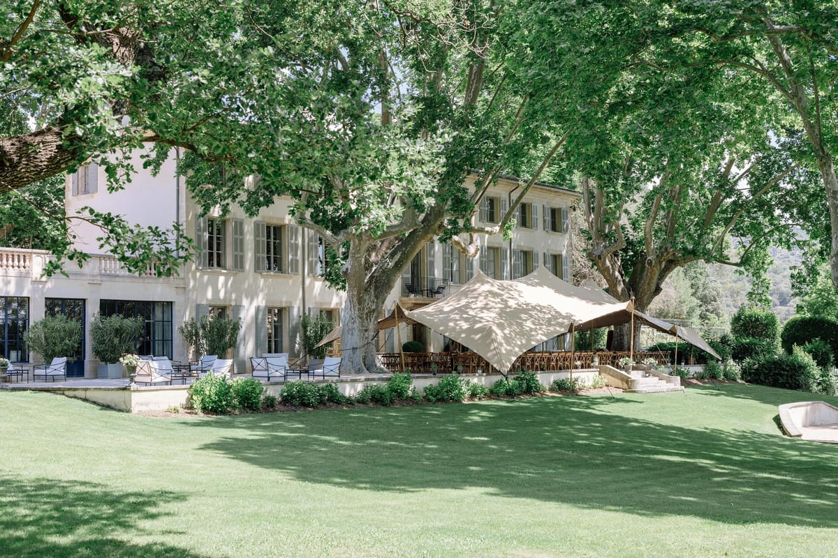 Panoramic view of the chateau, lawn and shaded lounge area