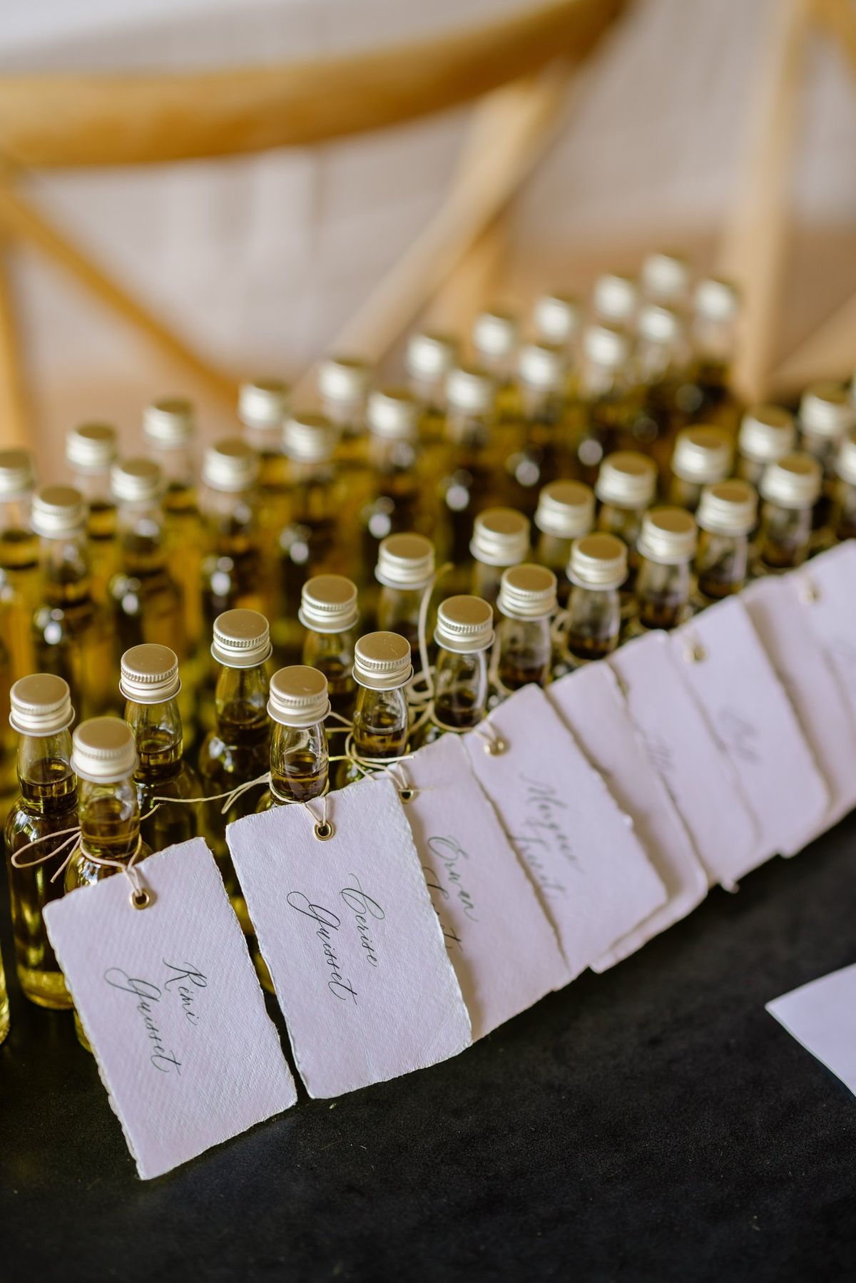 Favor bottles lined up with handwritten guest tags