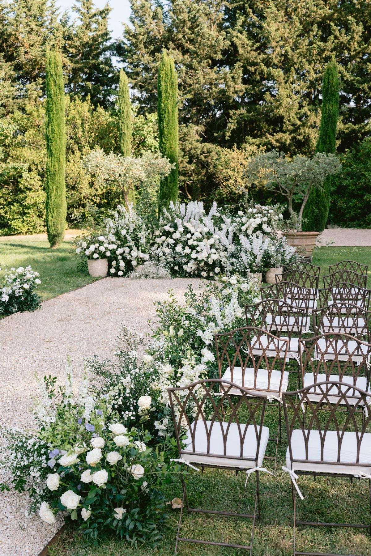 Outdoor ceremony aisle lined with white florals and cypress trees