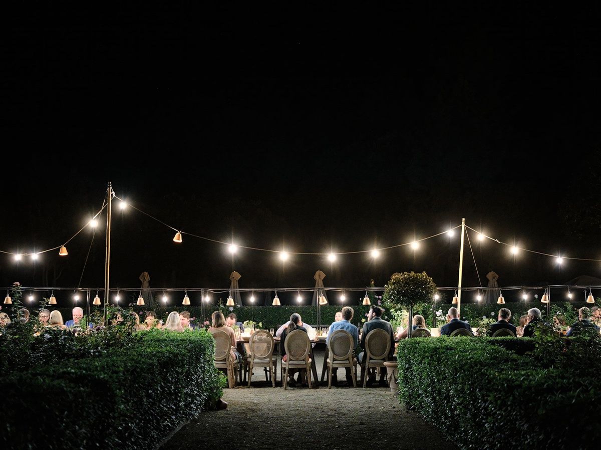 Evening reception under string lights with the chateau silhouette