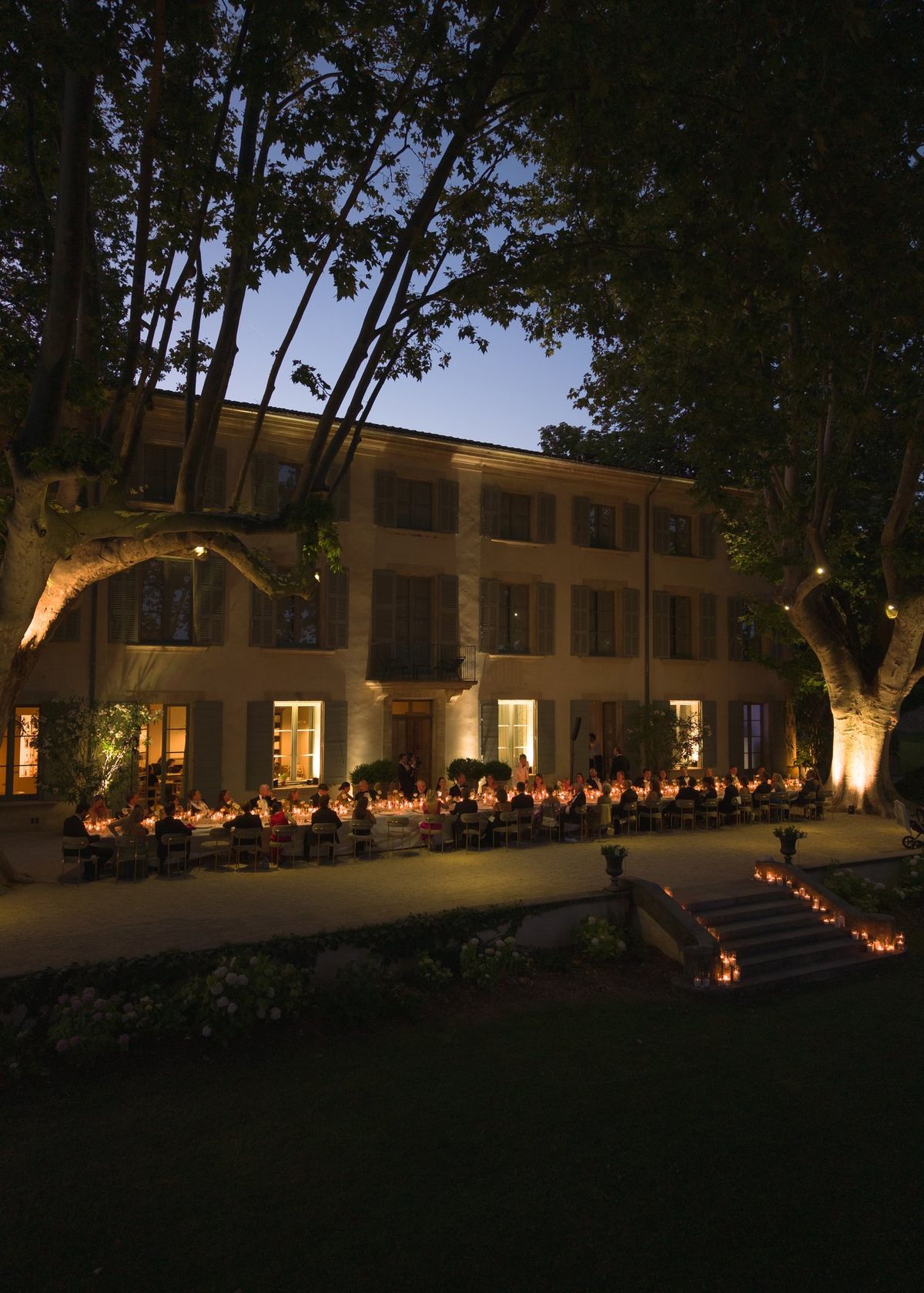 Chateau facade at dusk with a long dinner table set outside