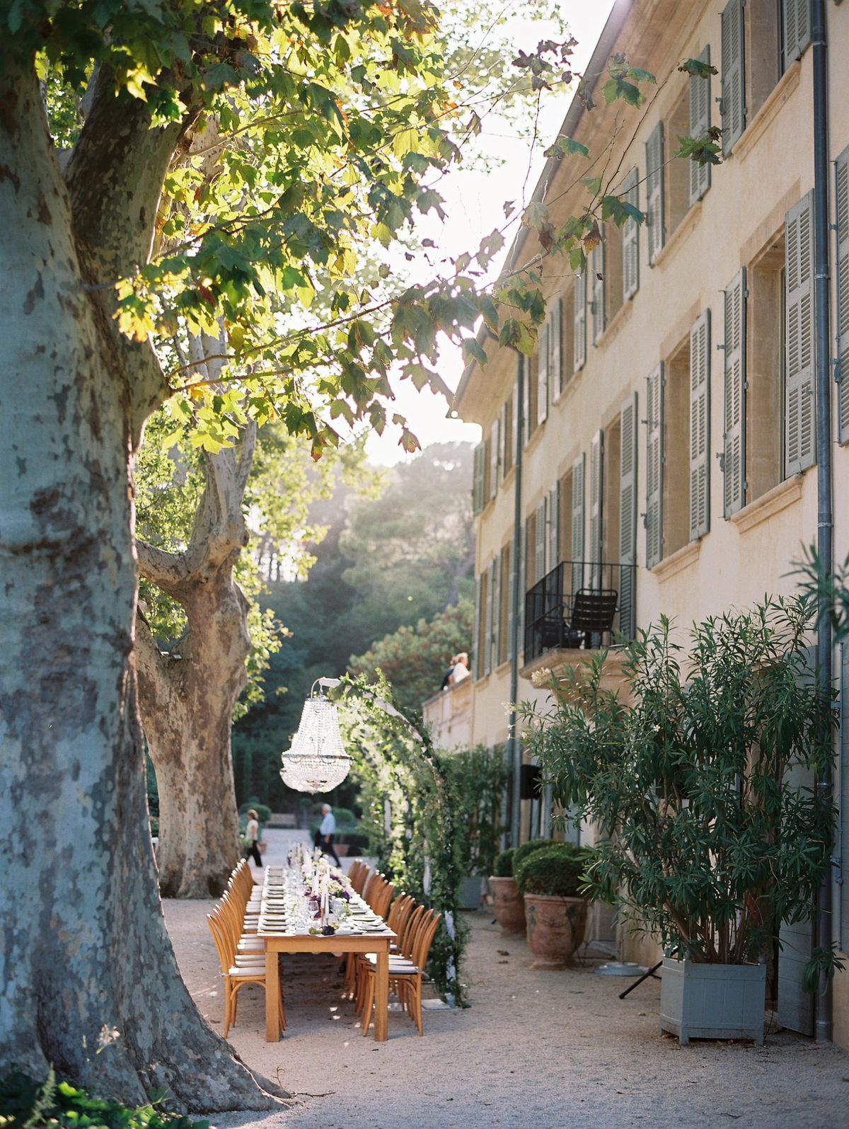 Outdoor dining area set beneath trees beside the chateau