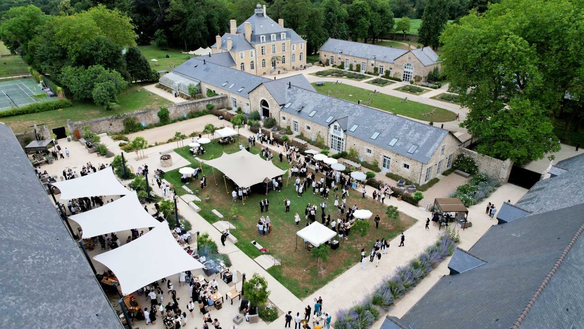 Guests gathered under stretch tents and shade sails in the courtyard at Domaine Le Mezo, seen from above