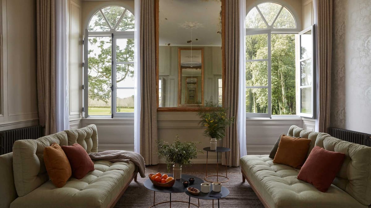Salon in the chateau at Domaine Le Mezo with arched windows, a gilt mirror and linen sofas