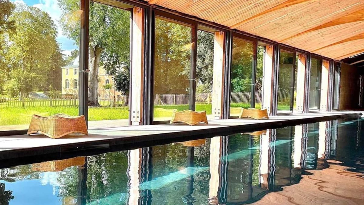 Indoor swimming pool at Domaine Le Mezo with sliding glass doors opening onto the park