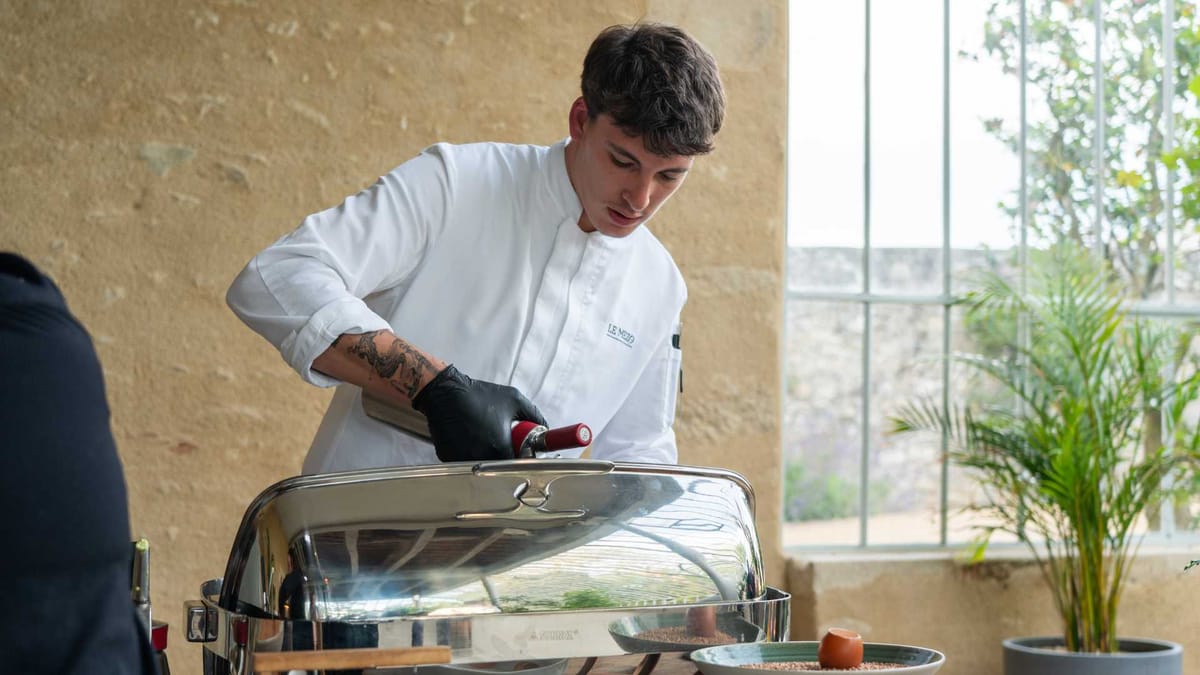 A chef in Le Mezo whites finishing a dish at a service station
