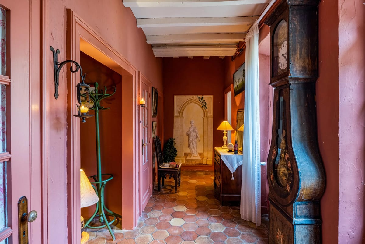 A terracotta-floored corridor with rose-pink walls and a tall grandfather clock