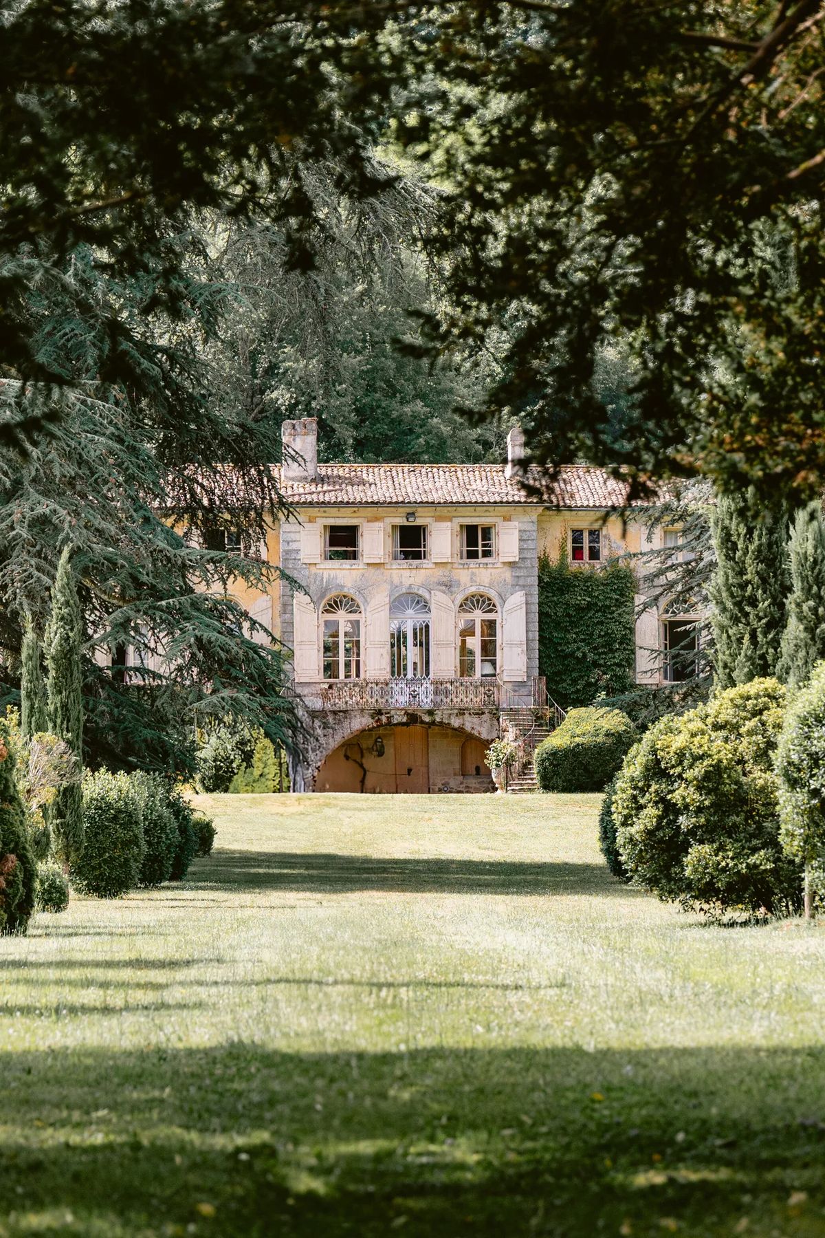 The chateau front elevation framed by mature trees across the lawn