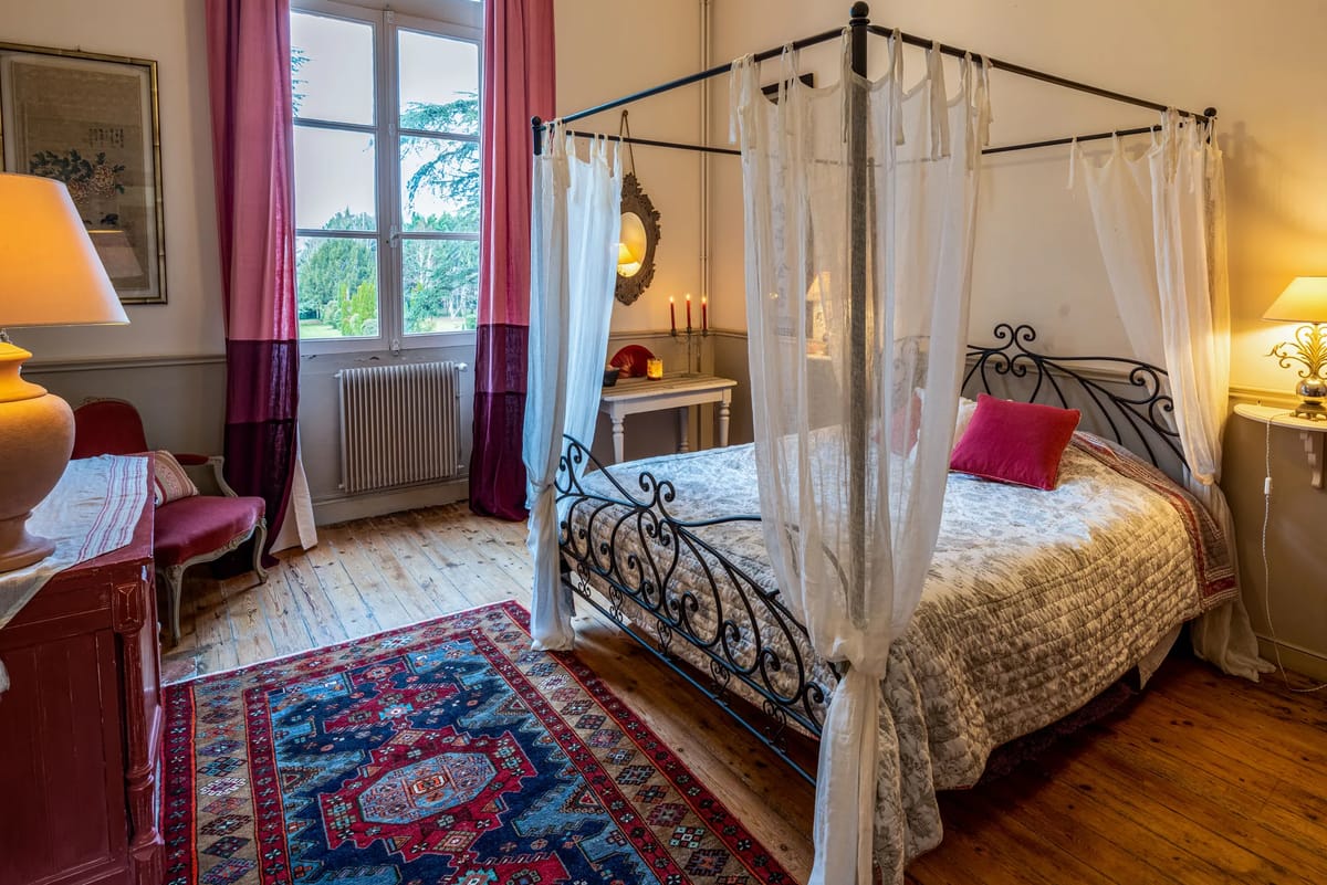 Guest bedroom with a wrought-iron four-poster bed and a patterned rug