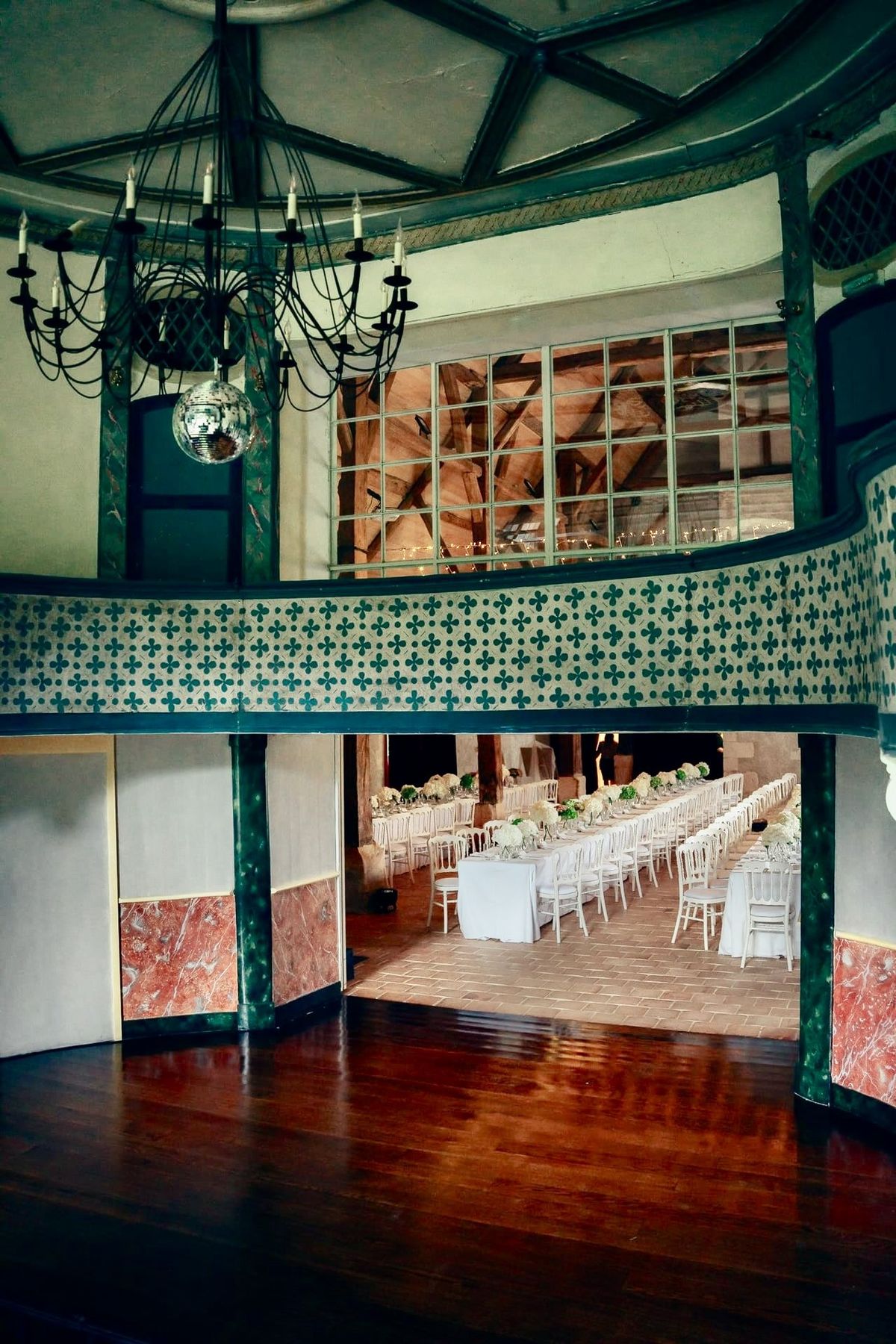 The 18th-century theatre's wooden dance floor, patterned balcony, chandelier and disco ball, opening onto the dinner barn
