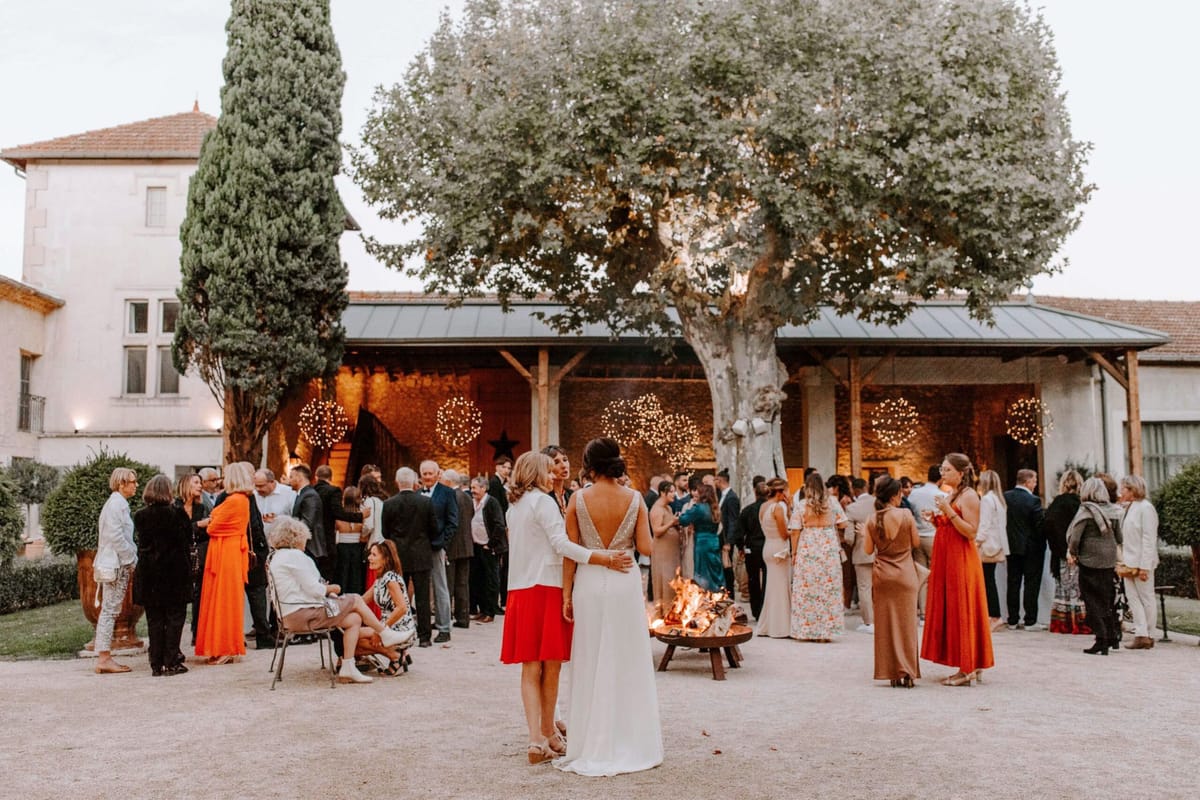 Mas D'Arvieux courtyard cocktail hour with guests around fire pit and fairy lit barn at dusk