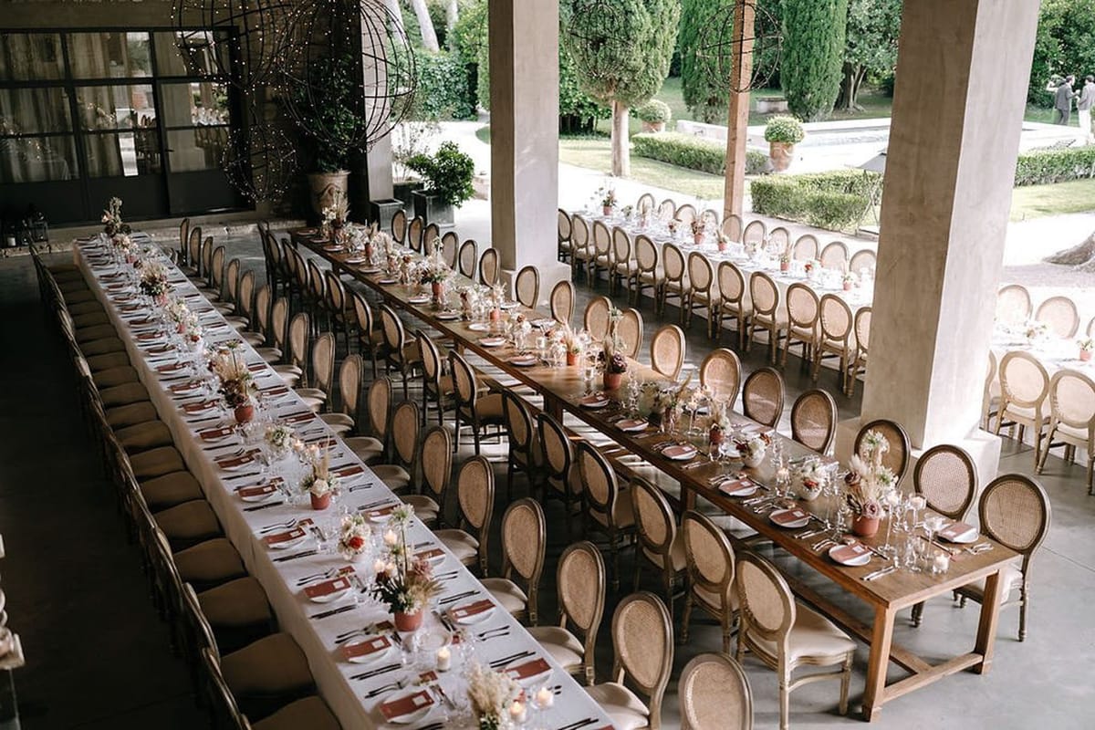 Mas D'Arvieux terrace wedding reception setup with long tables and cane chairs overlooking Provencal gardens