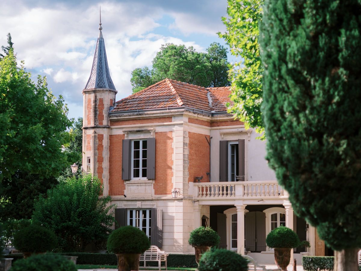 Mas D'Arvieux corner turret and stone facade framed by clipped garden topiary