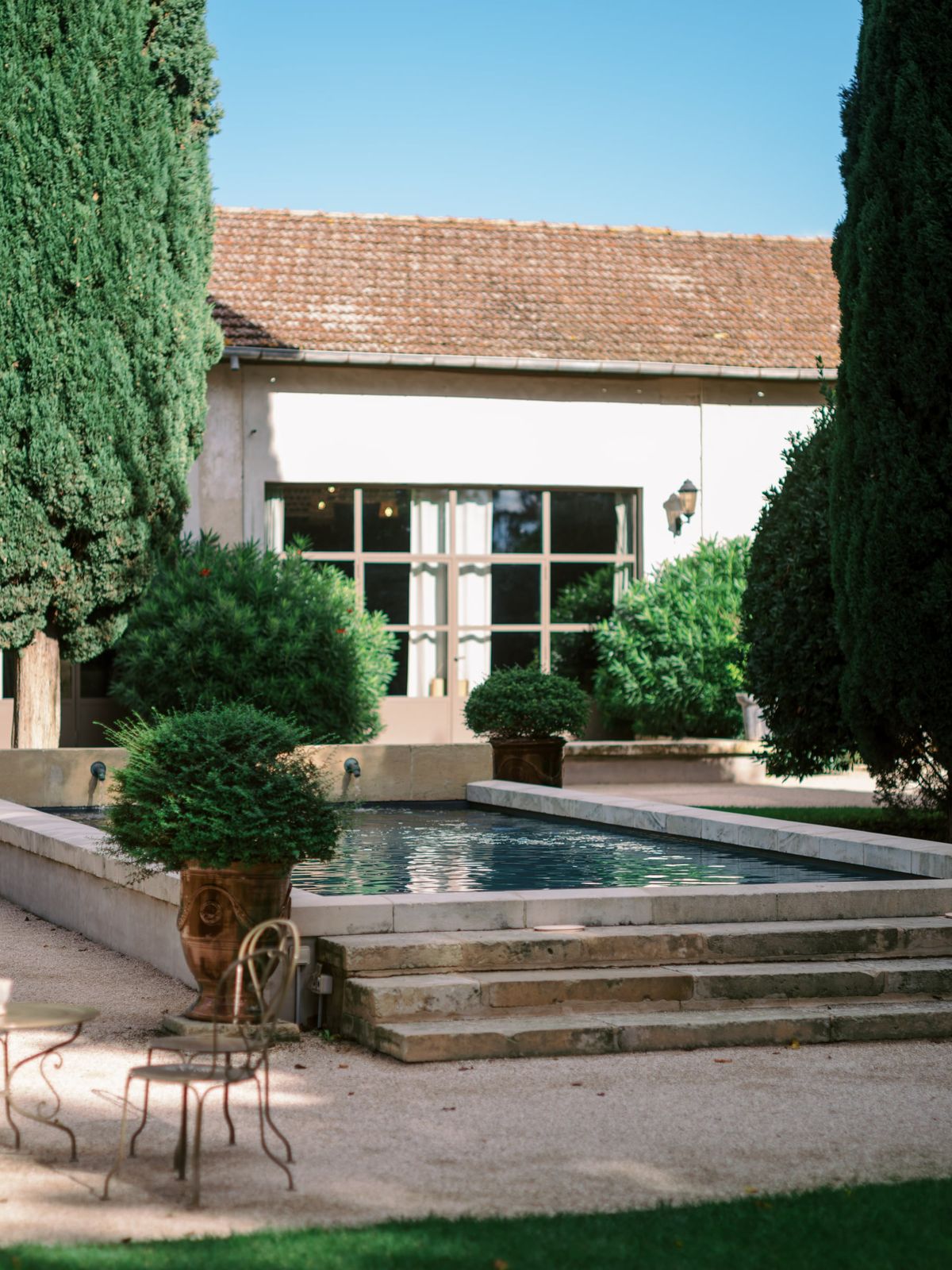 Mas D'Arvieux gravel courtyard lined with potted topiary and garden benches