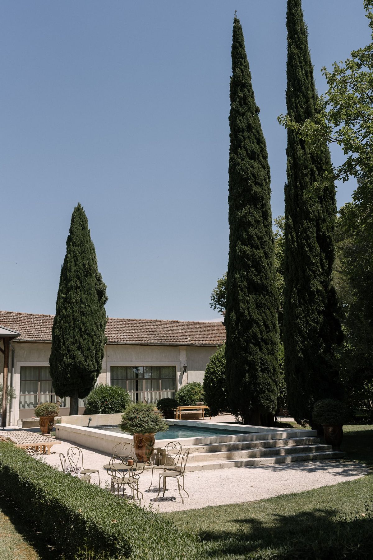 Mas D'Arvieux pool framed by cypress trees with garden seating