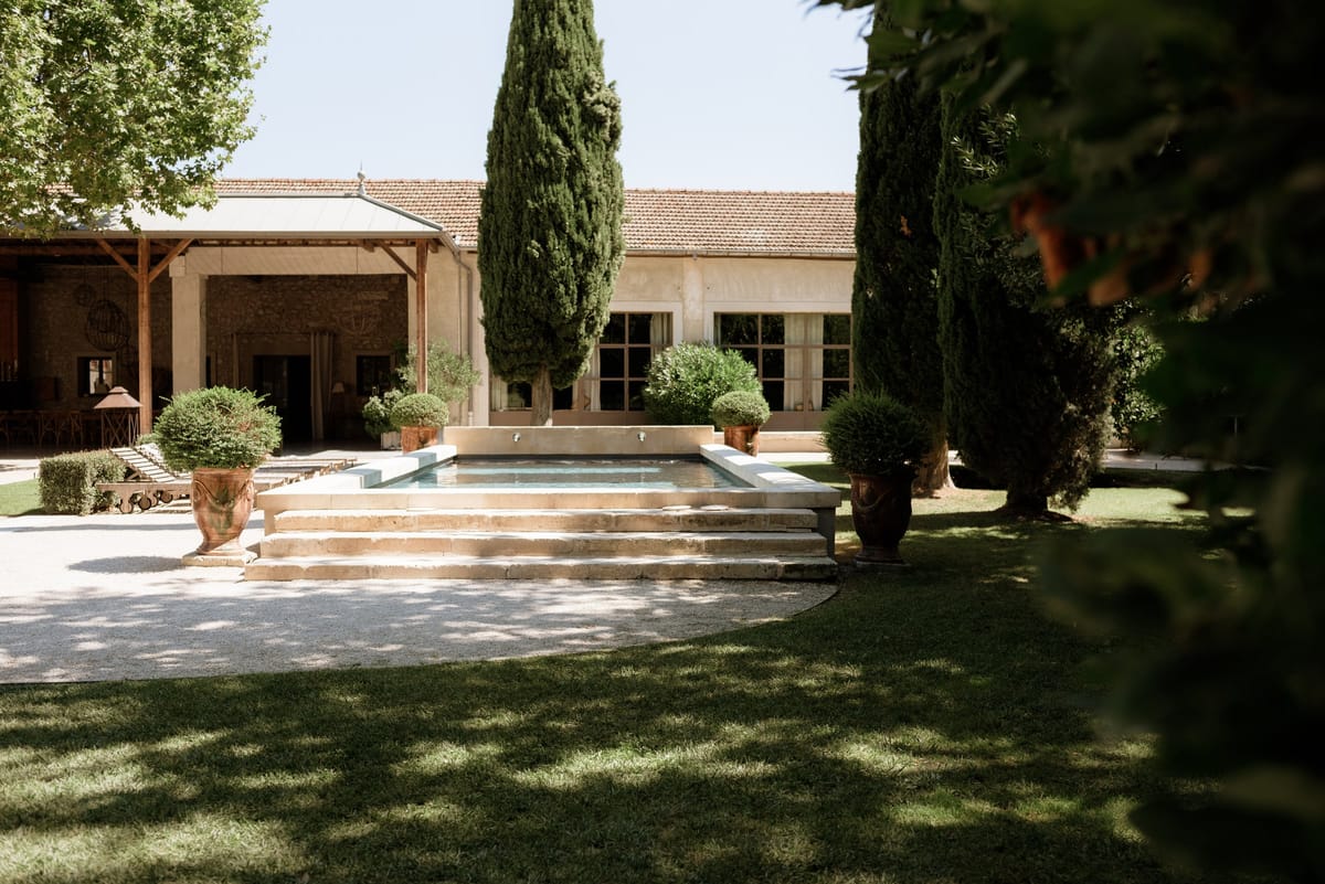 Mas D'Arvieux stone facade and corner turret framed by garden trees