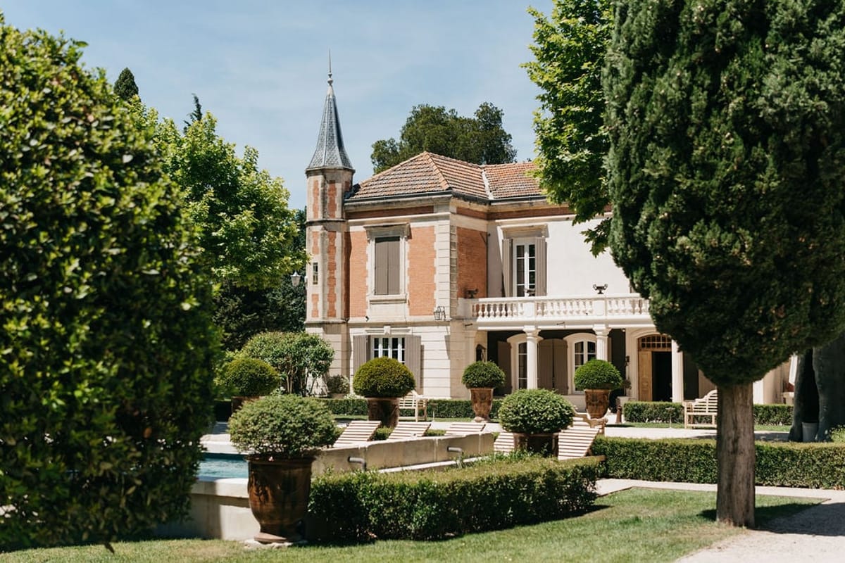 Mas D'Arvieux swimming pool, chateau and gardens framed by trees