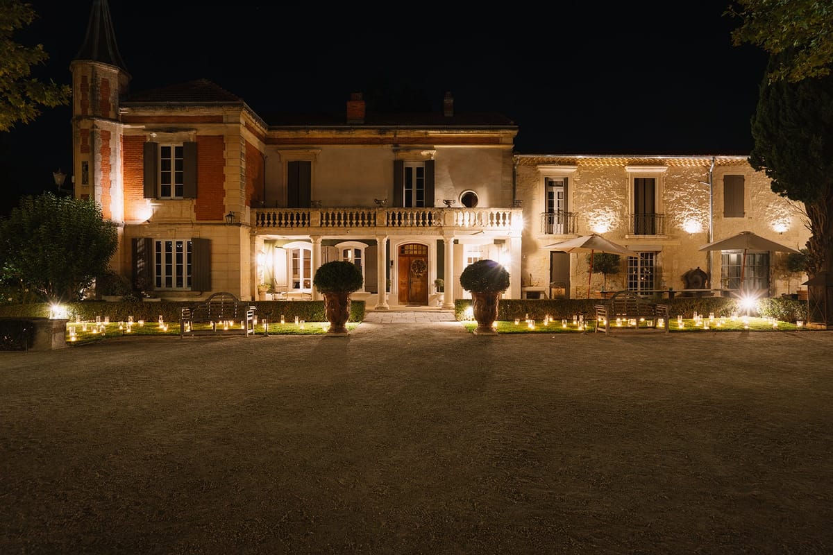 Mas D'Arvieux chateau facade lit at night with a candlelit garden path