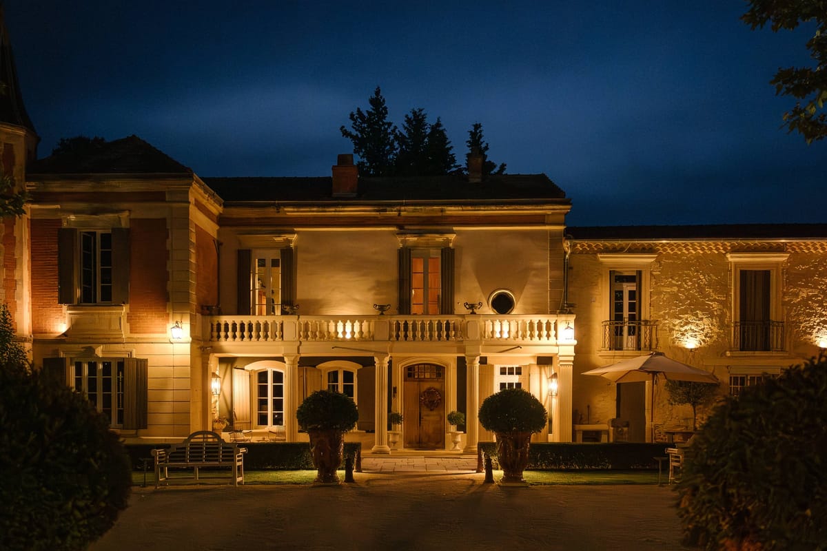 Mas D'Arvieux chateau facade illuminated at night with the entrance colonnade