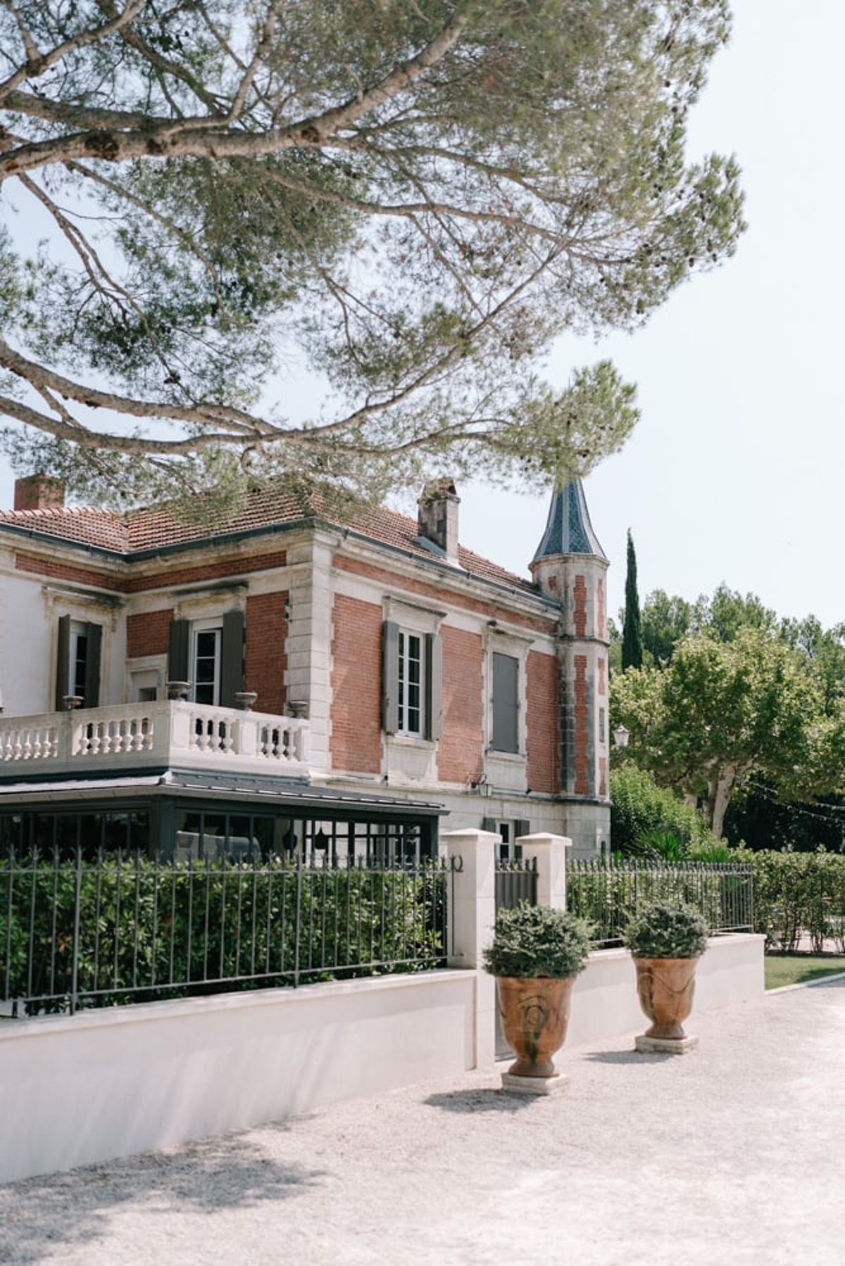 Mas D'Arvieux side facade and turret behind a wrought iron garden fence