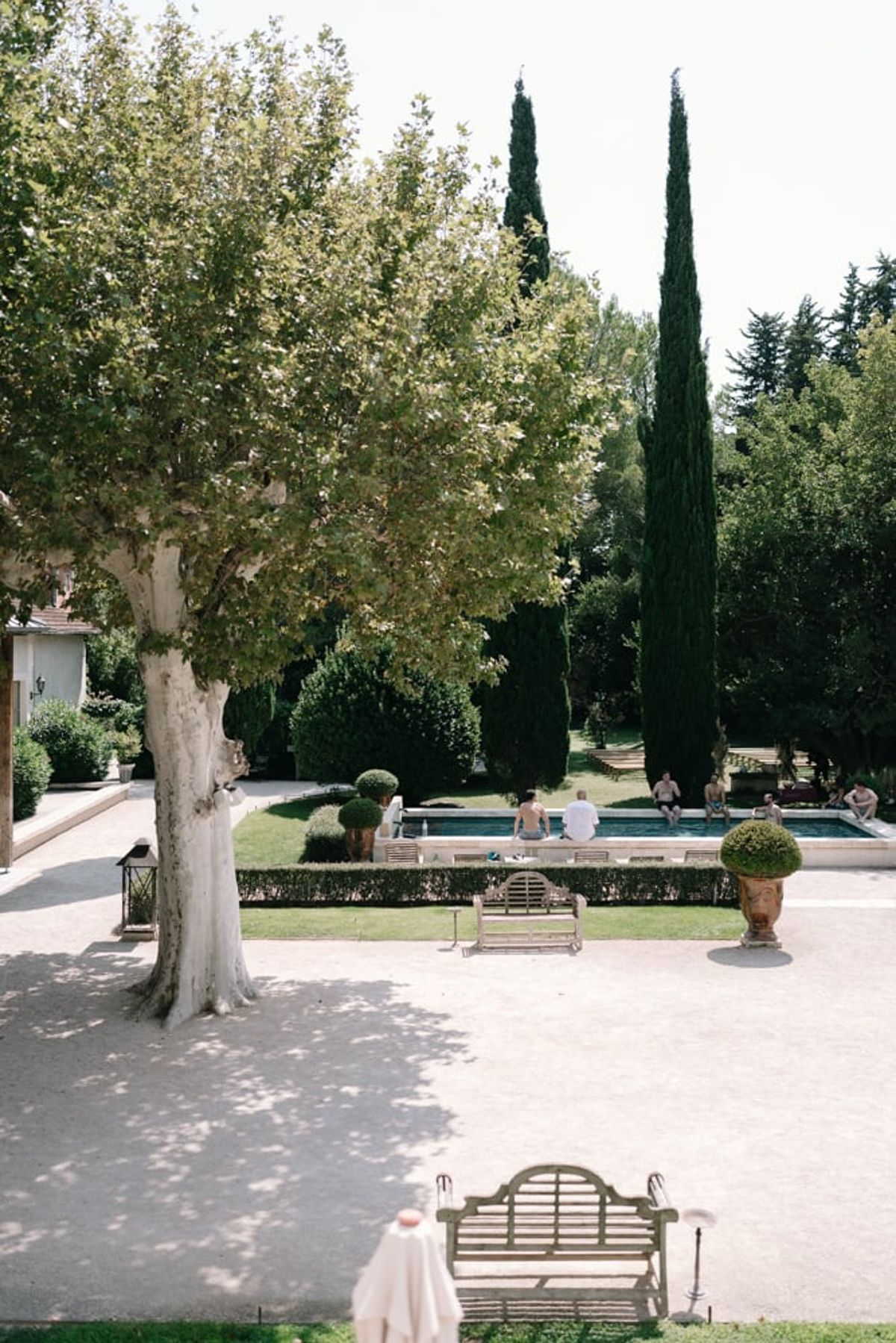 Mas D'Arvieux grounds overview with pool, garden benches and shade trees