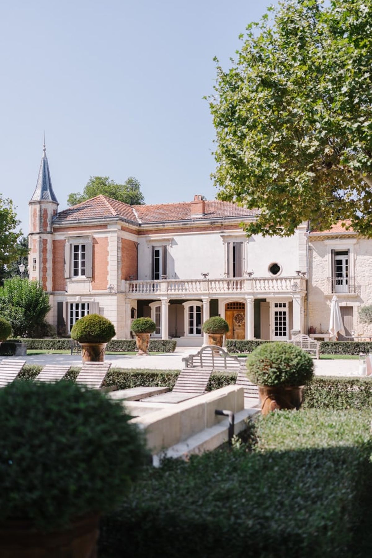 Mas D'Arvieux chateau facade and turret framed by garden trees