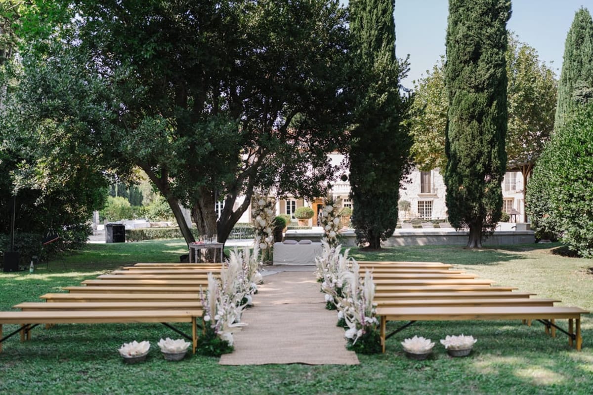 Mas D'Arvieux outdoor ceremony seating beneath shade trees facing the chateau