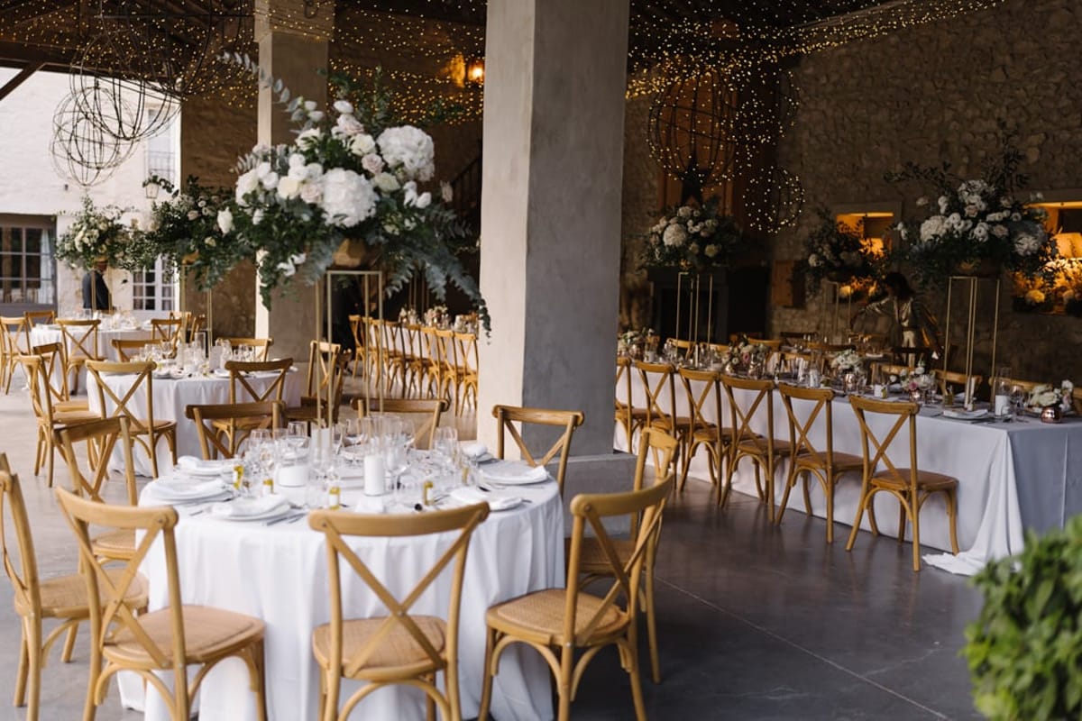 Mas D'Arvieux reception dinner set beneath the covered terrace with floral centrepieces
