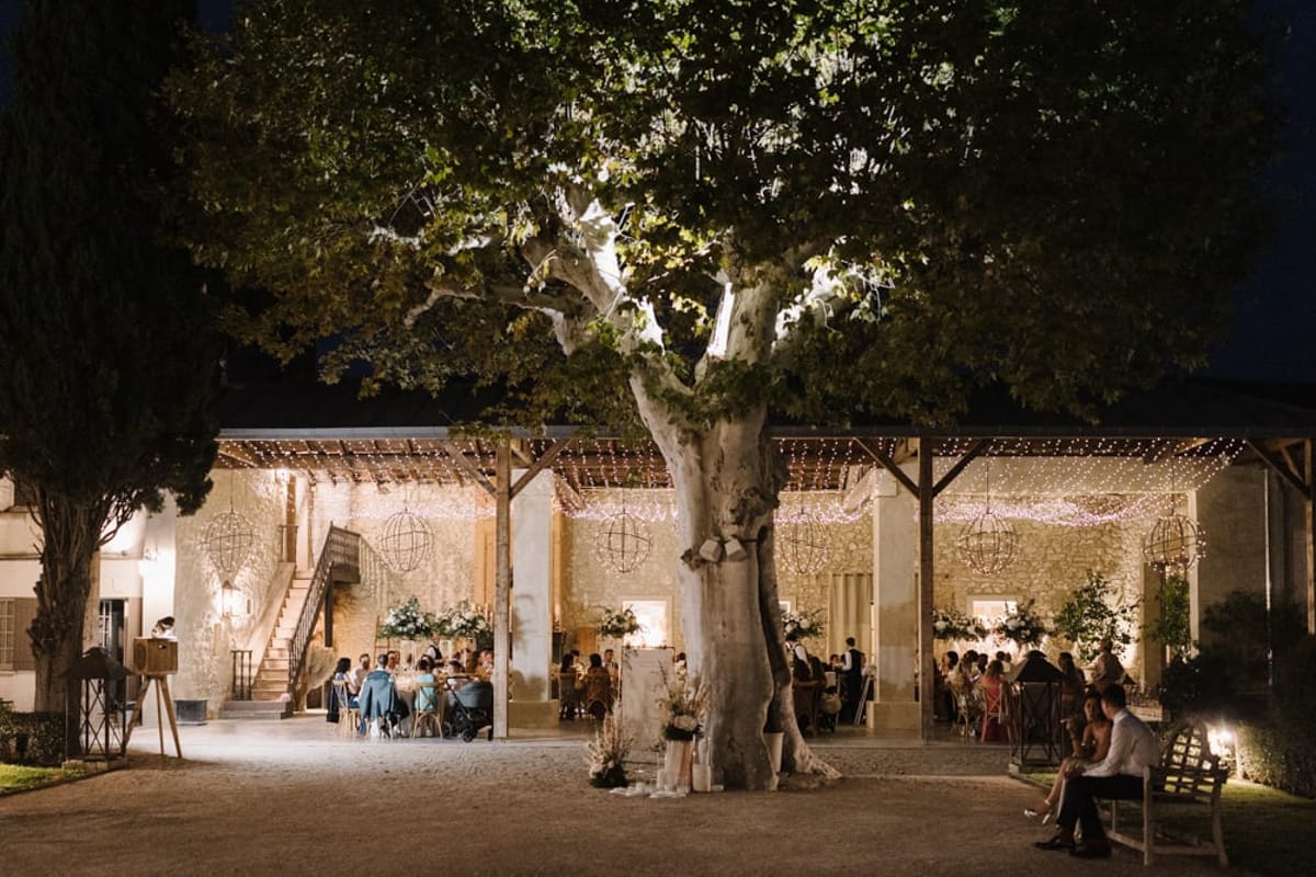 Mas D'Arvieux courtyard reception lit at night beneath a large plane tree