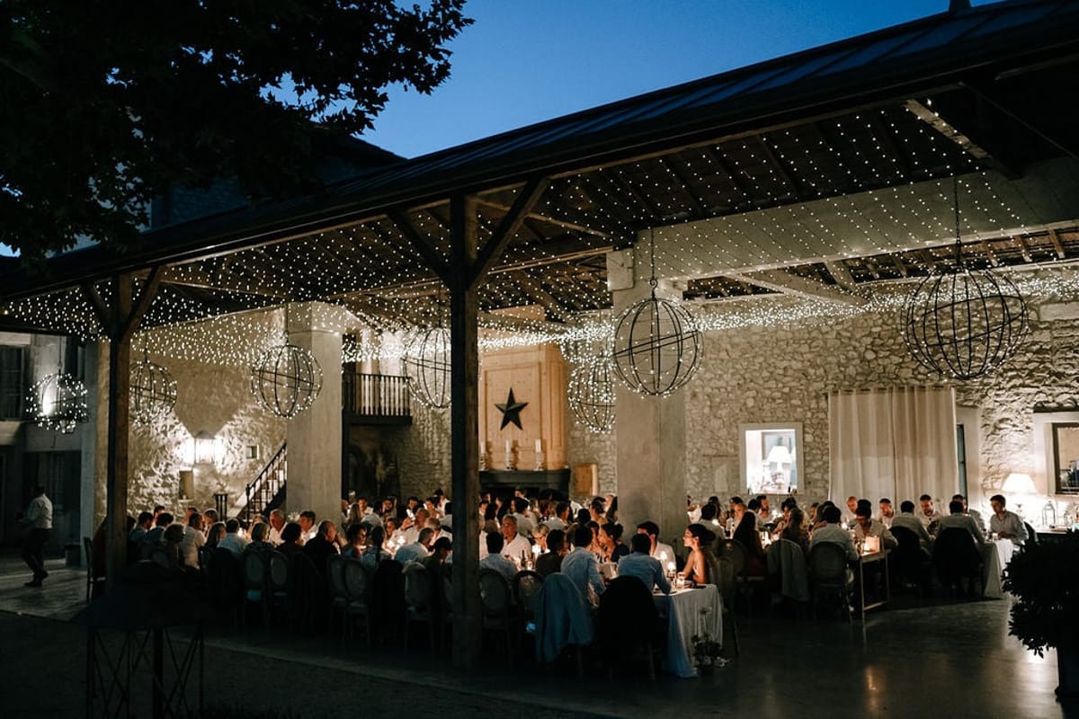 Mas D'Arvieux stone barn reception at dusk with string lights and guests dining