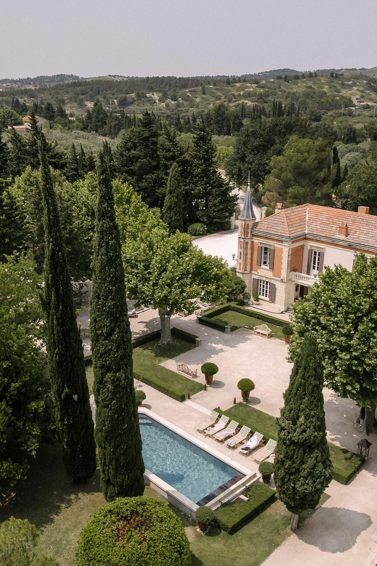 Aerial view of Mas D'Arvieux turret, pool and gardens framed by cypress trees