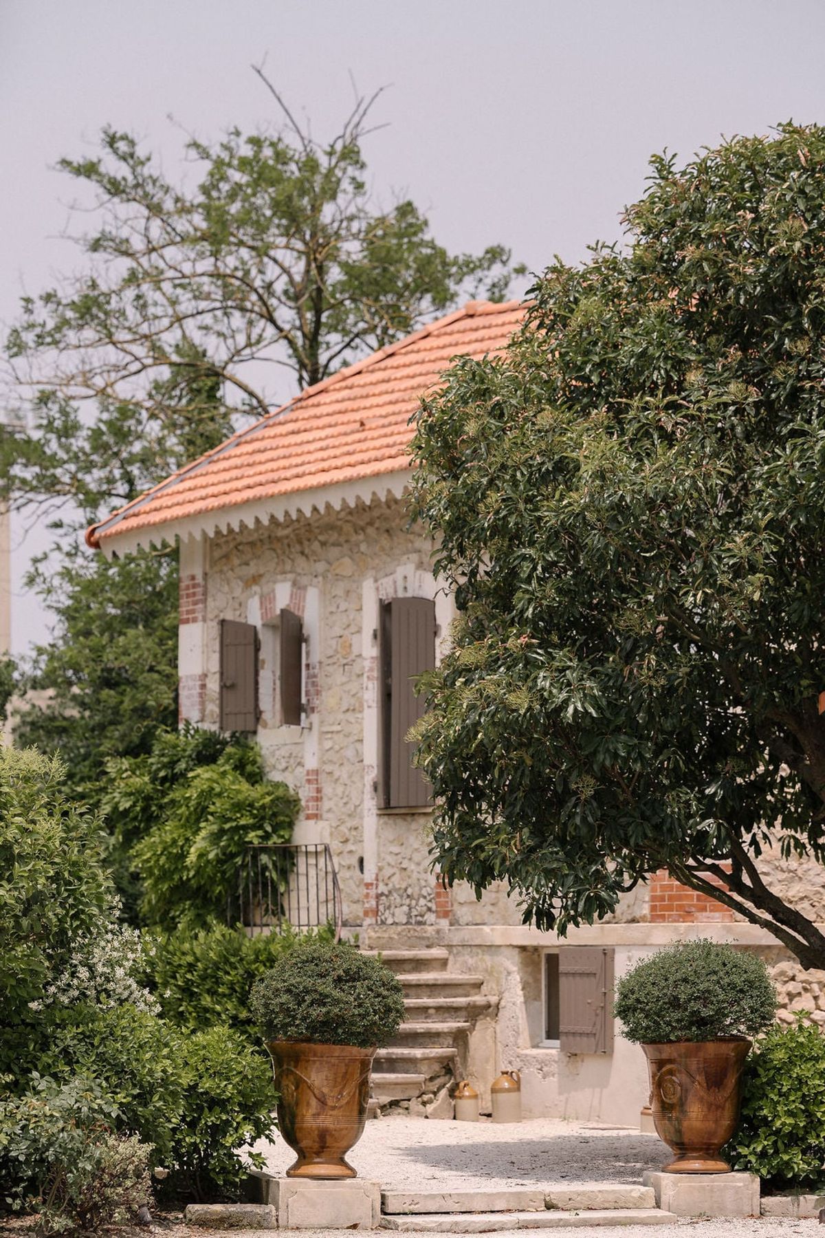 Mas D'Arvieux outbuilding with terracotta roof framed by garden urns