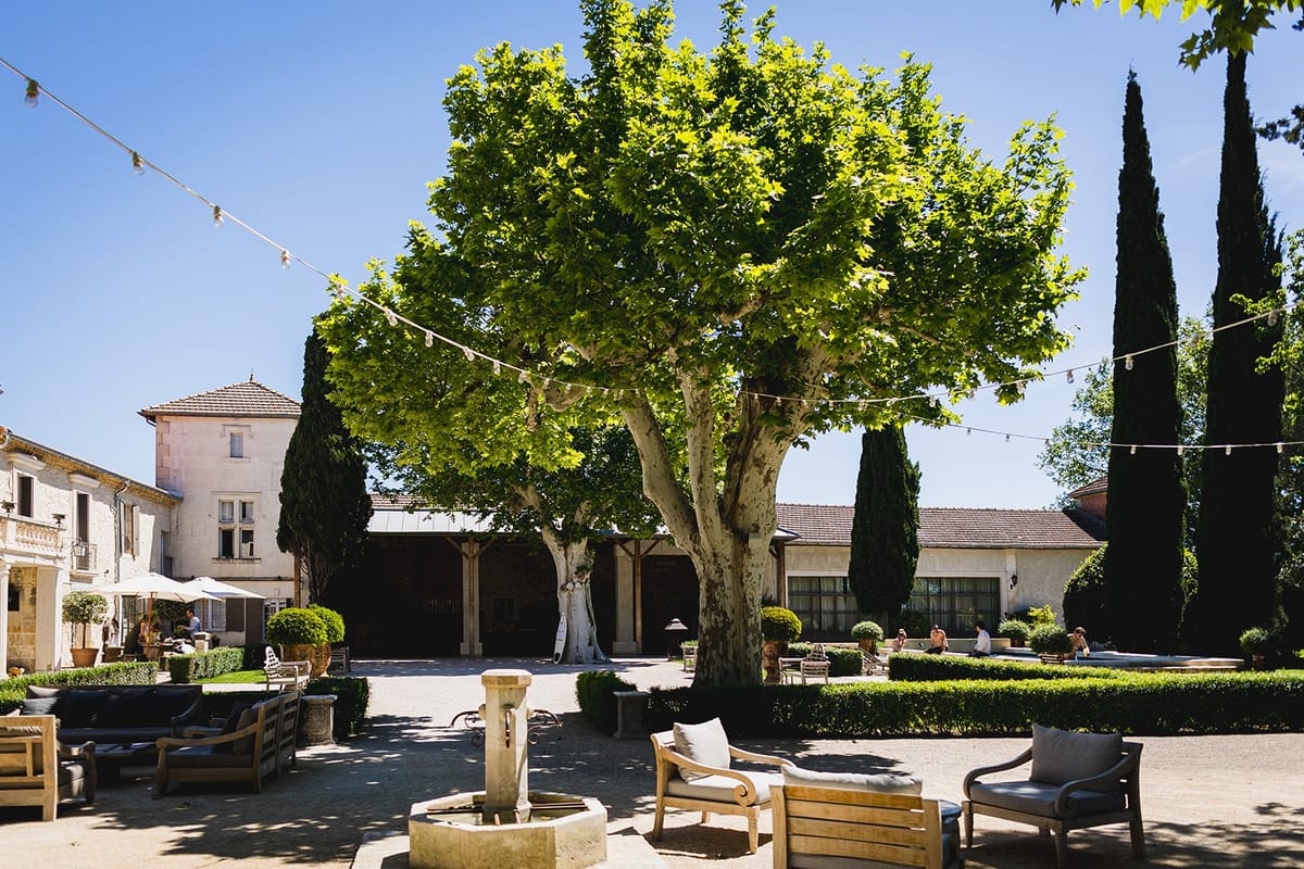 Mas D'Arvieux courtyard lounge area beneath a large plane tree with a stone fountain