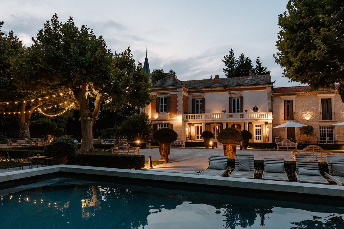Mas D'Arvieux chateau and pool lit at dusk beneath string lights