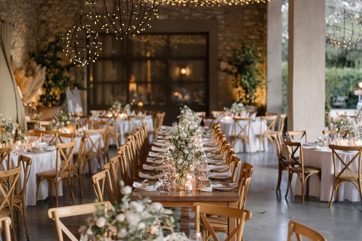 Mas D'Arvieux stone barn reception set beneath string lights and orb chandeliers