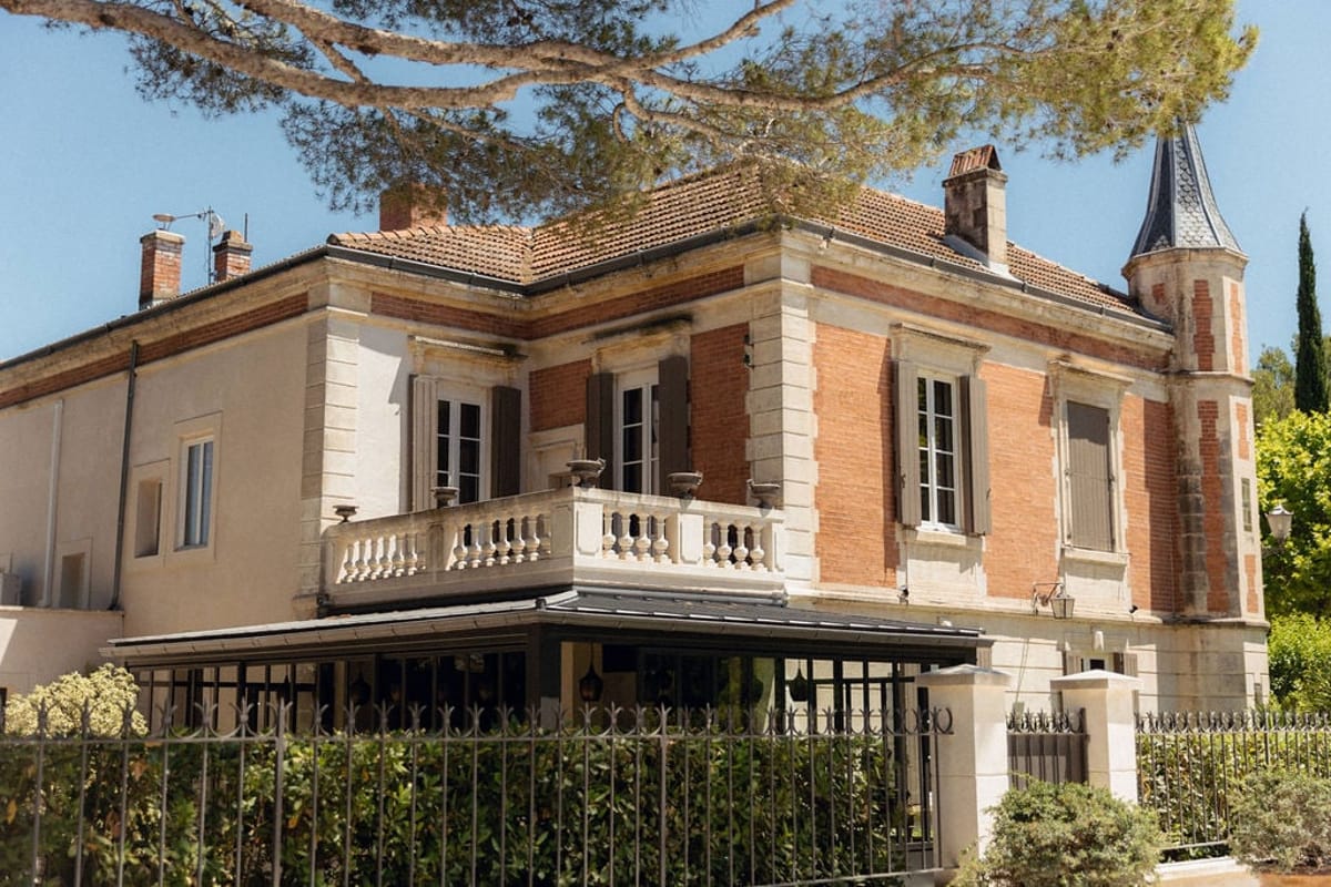 Mas D'Arvieux chateau facade and turret framed by garden trees