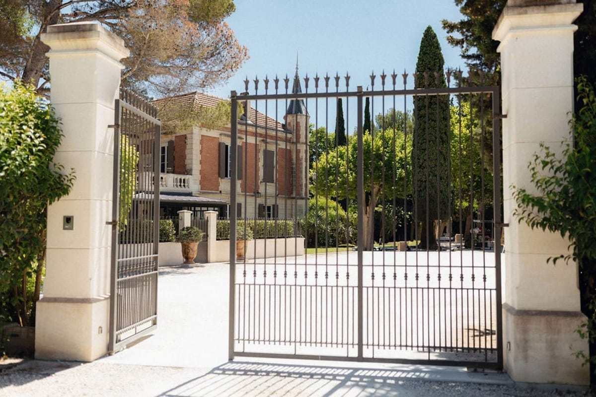 Mas D'Arvieux entrance gate and turret framed by cypress trees