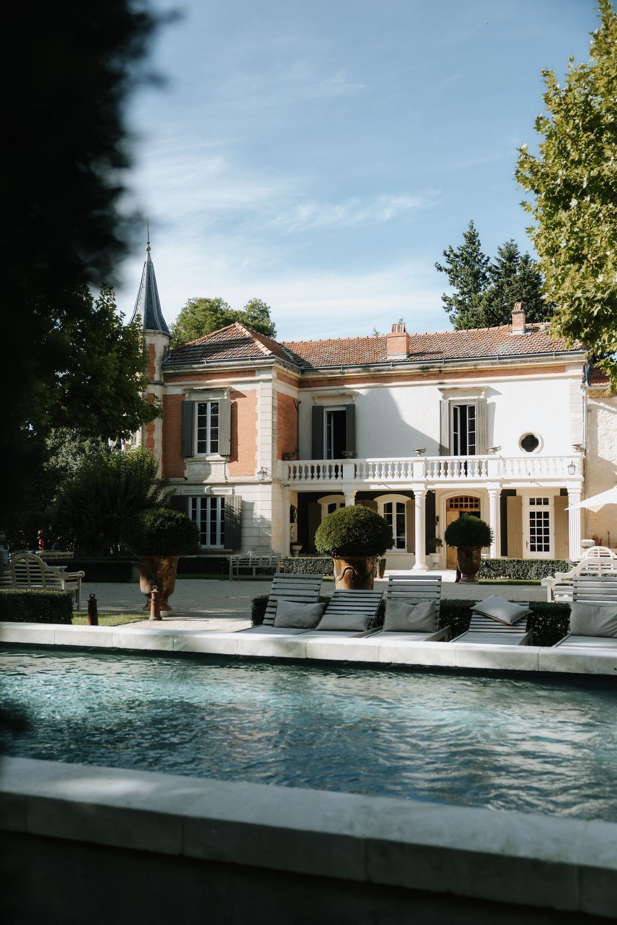 Mas D'Arvieux chateau facade and pool with lounge chairs on a summer day