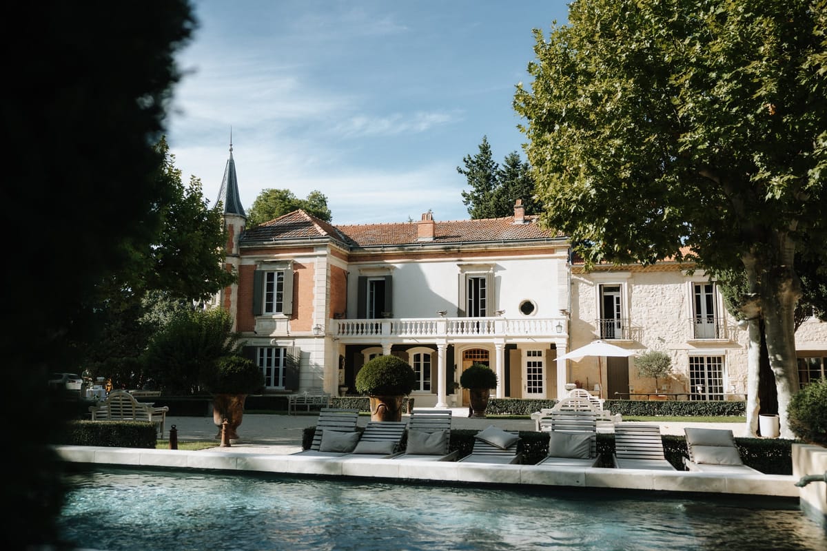 Mas D'Arvieux chateau facade and pool seen through the garden trees