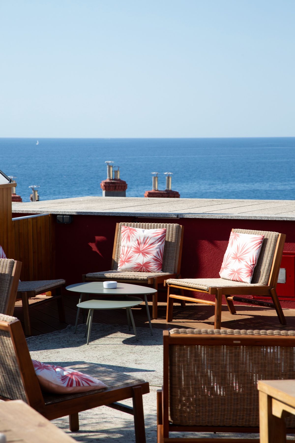 Rooftop terrace seating with rattan chairs and the Mediterranean behind