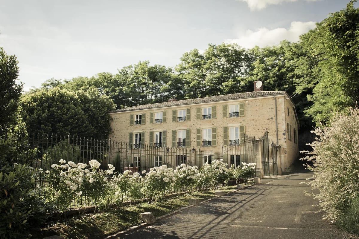 Stone facade of Domaine de Vavril's maison de maitre framed by a white rose hedge