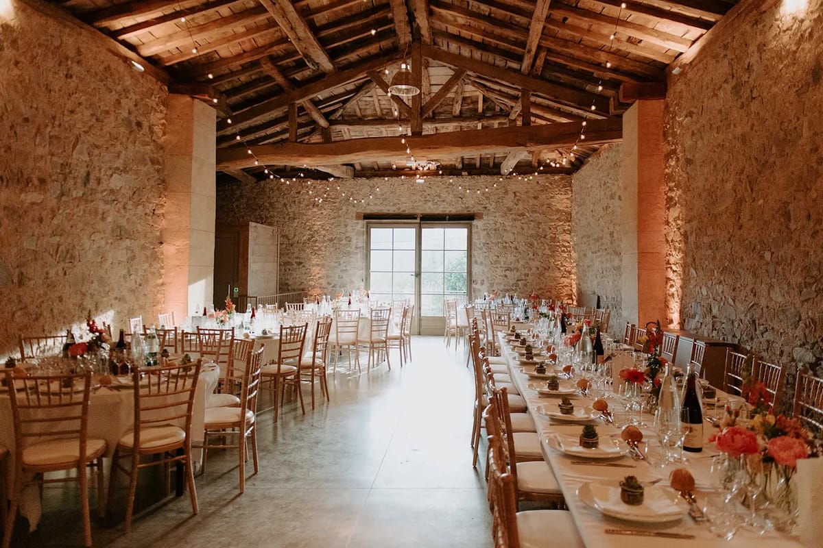 Stone reception barn at Domaine de Vavril set for a wedding dinner with festoon lights