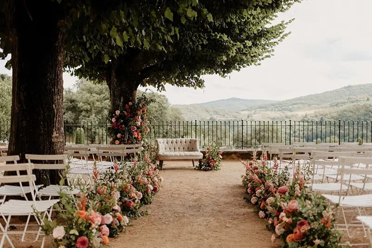 Outdoor ceremony terrace lined with pink and peach flowers at Domaine de Vavril, overlooking the vineyard hills