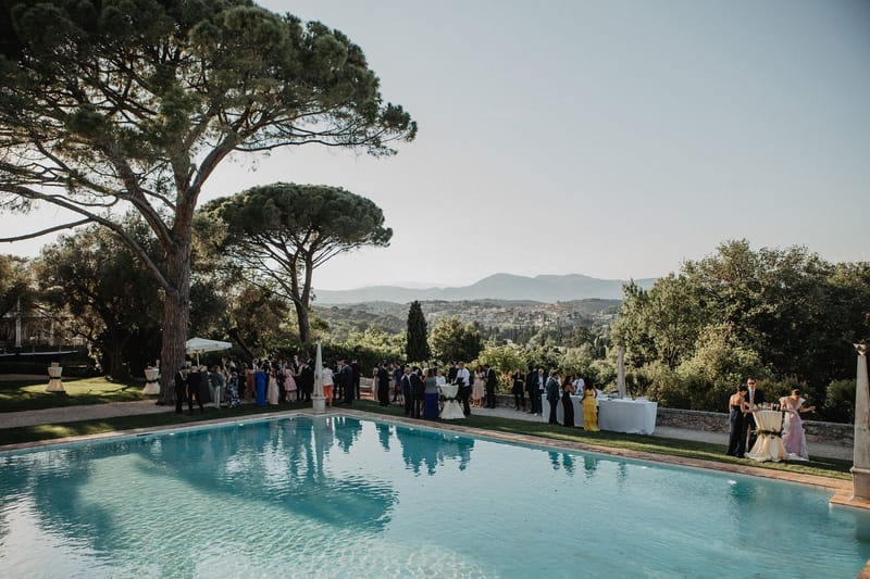 Elevated view of cocktail hour around swimming pool at hilltop estate with 50-60 guests and panoramic landscape backdrop