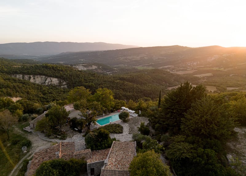 Aerial golden hour view of Provencal bastide with pool, cypress trees, and valley panorama