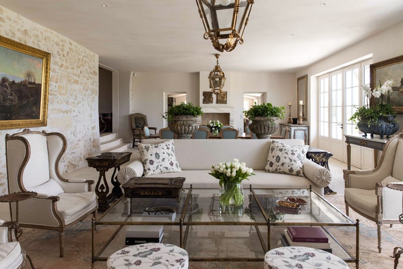 French chateau living and dining room with gilded armchairs, stone walls, topiaries, and duck-egg blue dining chairs